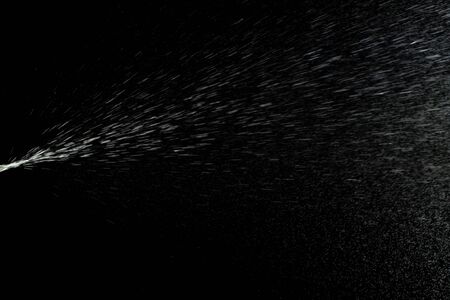 Spray water liquid perfume isolated on black background. Mist splash aerosol bottleの写真素材