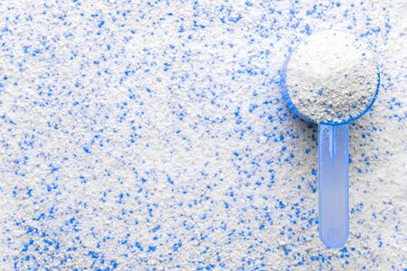 Detergent shirt. Soap white texture with scoop. Liquid powder in cup for washing machine. Laundry wash clothes background. Eco style cleaning conceptの写真素材