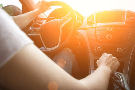 Happy driver inside car at sunset. Young woman have fun ride trip travel on road in summer sunny day. Drive vacation concept.の写真素材