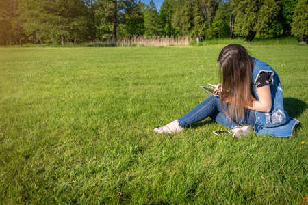 Student girl person work on tablet, computer in summer park. Online woman in nature outside. Laptop outdoor business technology. Electronic gadgets distance learning concept.の写真素材