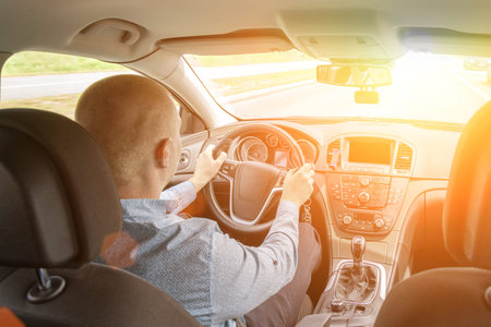 Driver training car on road in summer sunny day. Happy young man inside vehicle driving. Vacation...
