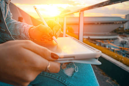 Computer outdoor. Student woman working on laptop, tablet in summer park. Girl person business nature outside with online technology. Electronic gadgets distance learning conceptの写真素材