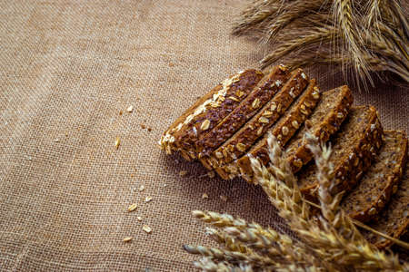 Home baked bread. Rye bakery with crusty loaves and crumbs. Fresh rustic traditional bread with wheat grain ear or spike plant on natural cotton background. Design element for bakery product label.の写真素材