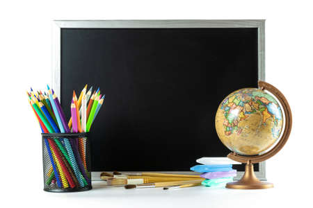 School background. School stationery with colorful pencils, chalk, globe on black chalkboard in classroom. Design Copy Space Supplies.の写真素材