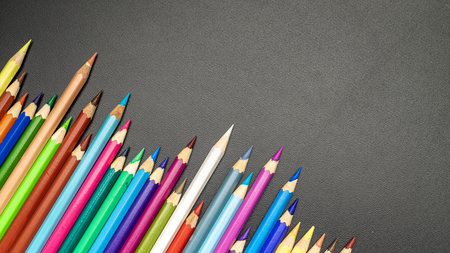 Education concept. School stationery with colorful pencils, chalk, brushes on black chalkboard in...