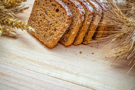 Traditional bread. Fresh loaf of rustic traditional bread with wheat grain ear or spike plant on wooden texture background. Rye bakery with crusty loaves. Design element for bakery product label.の写真素材