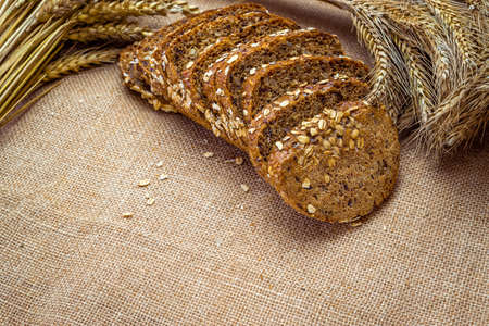 Rye bread. Bakery with crusty loaves and crumbs. Fresh loaf of rustic traditional bread with wheat grain ear or rye spike plant on natural cotton background. Healthy Food concept.の写真素材