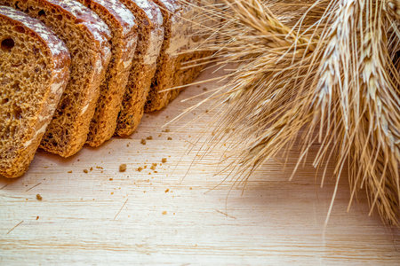 Home baked bread. Rye bakery with crusty loaves and crumbs. Fresh rustic traditional bread with wheat grain ear or spike plant on natural wooden background. Design element for bakery product label.の写真素材