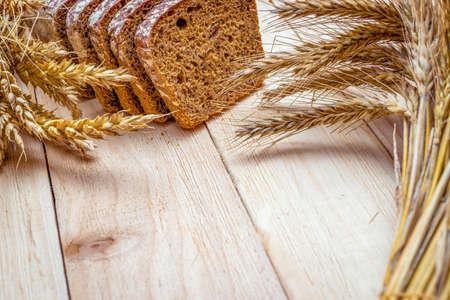 Rustic bread. Fresh loaf of rustic traditional bread with wheat grain ear or spike plant on wooden texture background. Rye bakery with crusty loaves and crumbs. Concept - Cooking at Homeの写真素材