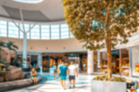 Young people shopping mall blurred background. Interior of retail center store in soft focus. People shopping in modern commercial mall center. Fashion market hallの写真素材