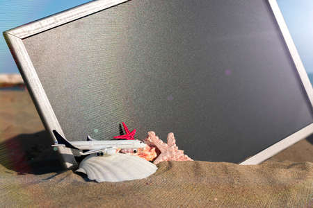 Sea background. Starfish, seashells, toy plane and globe near blackboard on ocean nature beach. Summer vacation and product advertisement conceptの写真素材