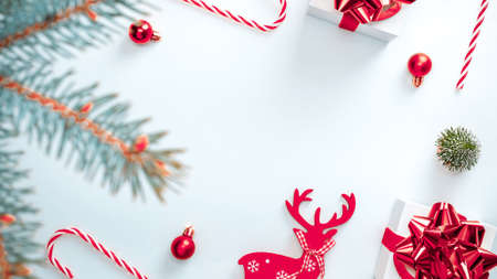 Gifts background. White gift box with red ribbon, New Year balls and winter tree in Christmas composition on white background for greeting card. Flat lay, top view, copy spaceの写真素材