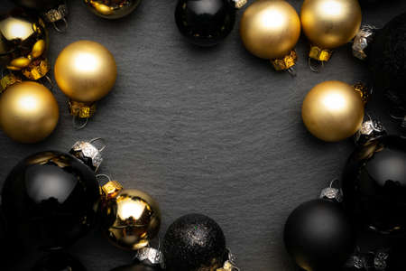 Xmas background golden. Golden New Year balls, black baubles in xmas composition on dark textured background for greeting card. Decoration and copy space for your text.の写真素材