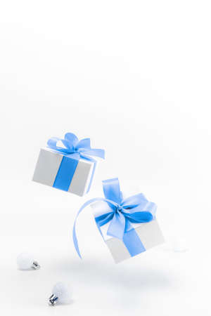 Holiday winter blue. White gift box with blue ribbon, New Year balls in Christmas composition on white background for greeting card. Copy space. Winter holidays, New Yearの写真素材