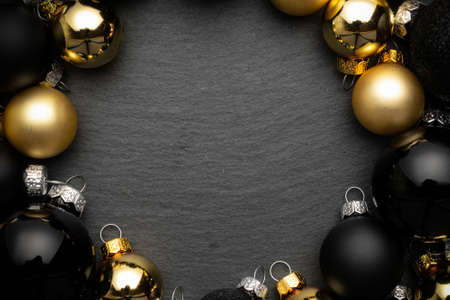 Xmas decoration. Golden New Year balls, black baubles in xmas composition on dark textured background for greeting card. Flat lay, top view, copy space.の写真素材