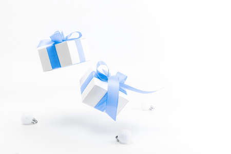 Christmas gift. White gift box with blue ribbon, New Year balls in xmas composition on white background for greeting card. Winter festive composition with copy space.の写真素材