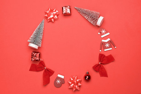 Christmas ornaments. Stocking, gifts, winter tree, ribbon and bow in shape frame on red background...