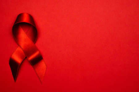 Cancer ribbons. Red ribbon symbol in hiv world day on dark red background. Awareness aids and cancer.の写真素材