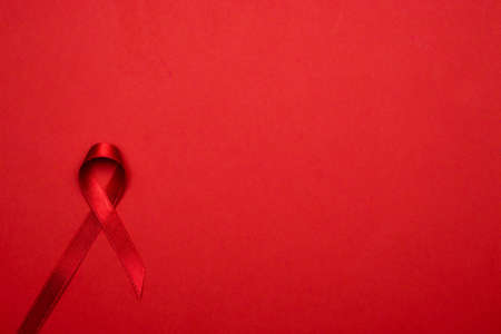 Infection symbol. Red ribbon symbol in hiv world day on dark red background. Awareness aids and cancer. Healthcare and medical conceptの写真素材