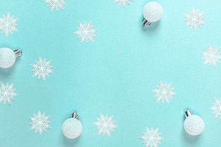 Holiday xmas background. White snowflakes, Silver balls in Christmas composition on pastel blue...