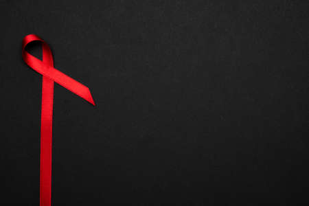 Breast cancer woman. Red ribbon symbol in hiv world day on dark background. Awareness aids and cancer. Healthcare and medical conceptの写真素材