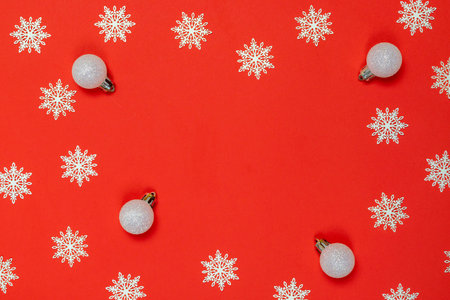 Xmas pattern. White snowflakes, silver balls in Christmas composition on red background for greeting...
