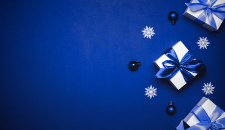 Gift boxes cyan. White gifts with cyan ribbon, New Year balls and winter tree in Christmas composition on dark blue background for greeting card. Xmas backdrop with space for textの写真素材