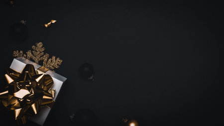 Xmas decoration. White gift with golden bow, gold balls and sparkling lights garland in Christmas decoration on dark background for greeting card. Flat lay, top view, copy spaceの写真素材