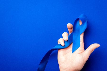 Prostate awareness. Blue ribbon in hands isolated on deep blue background. Awareness prostate cancer of men health in November. Healthcare, International men, Father dayの写真素材
