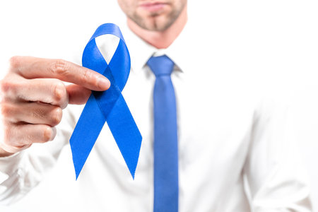Blue prostate ribbon. Awareness cancer of men health. Hipster men in bright shirt, cyan tie with blue ribbon in hands on white background. November and International Mens Dayの写真素材