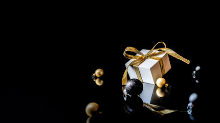 Happy 2021. White gift box with golden ribbon, New Year balls and winter tree in Christmas composition on black background for greeting card. Decoration and copy space for your textの写真素材