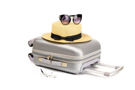 Baggage isolated. Travel accessories with suitcase, straw hat, toy airplane in minimal trip vacation concept isolated on white background. Summer vacation and product advertisement conceptの写真素材