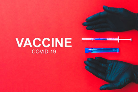 Vaccine development. Doctor hand in medical glove hold syringe with needle for protection flu virus and coronavirus. Covid vaccine isolated on red. Health care in hospitalの写真素材