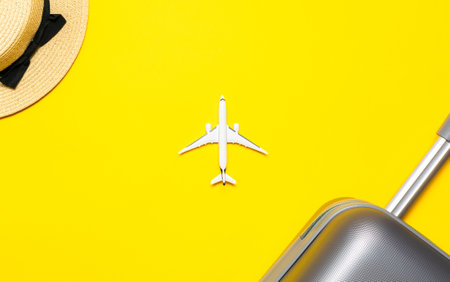 Summer holiday poster. Womens accessories traveler: suitcase, white plane, sunglasses on yellow background with empty space for text. Summer vacation and product advertisement conceptの写真素材