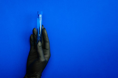 Syringe isolated. Doctor hand in medical glove hold test tube or bottle for protection flu virus and coronavirus. Covid vaccine isolated on blue. Concept fight against virus covid-19の写真素材