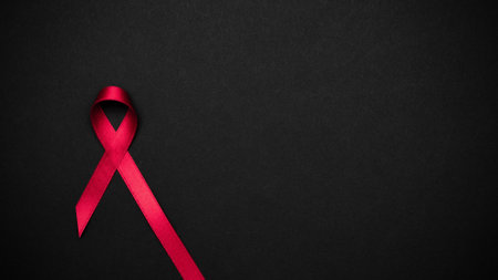 Hiv support. Red ribbon symbol in hiv world day on black background. Awareness aids and cancer. Aging health month conceptの写真素材