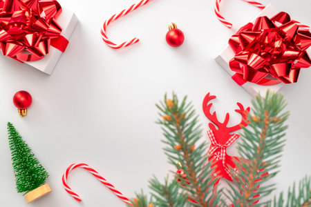 Gift boxes background. White gift box with red ribbon, New Year balls and sparkling lights in Christmas composition on white for greeting card. Winter festive composition with copy spaceの写真素材