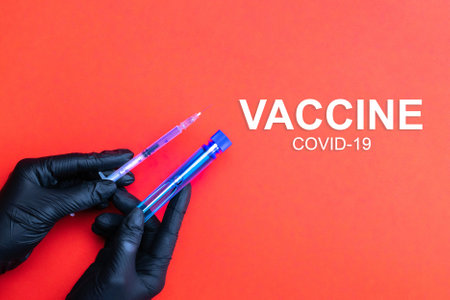 Syringe hand. Doctor hand in medical glove hold syringe with needle for protection flu virus and coronavirus. Covid vaccine isolated on red. Concept: diseases, medical care, scienceの写真素材