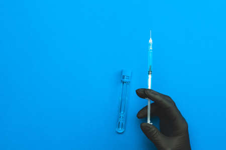 Syringe isolated. Doctor hand in medical glove hold syringe with needle for protection flu virus vaccine isolated on blue. Concept fight against virus covid-19の写真素材