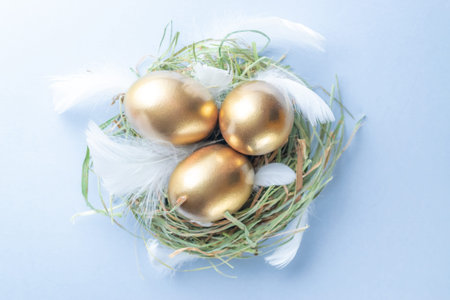 Easter eggs Golden color in basket with white feathers on pastel blue background in Happy Easter...
