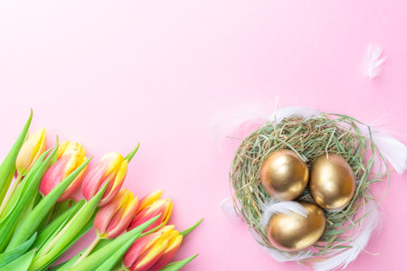 Easter eggs basket. Golden egg in basket with spring tulips, white feathers on pastel pink...