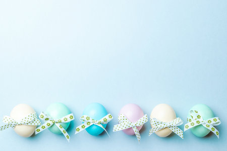 Easter luxury. Colorful egg with tape ribbon on pastel blue background in Happy Easter decoration. Flat lay, top viewの写真素材