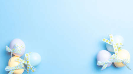 Easter eggs isolated. Colorful egg with tape ribbon on pastel blue background in Happy Easter decoration. Flat lay, top viewの写真素材