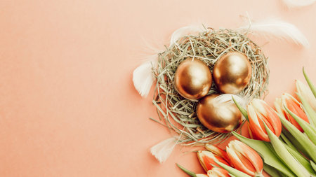Easter Golden eggs in basket with spring tulips, white feathers on pastel pink background in Happy...