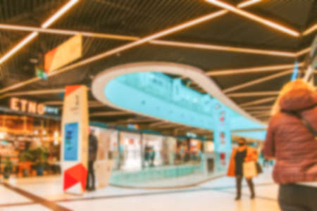 Shopping mall entrance blurred background. People shopping in modern commercial mall center. Interior of retail center store in soft focus. Image for background useの写真素材
