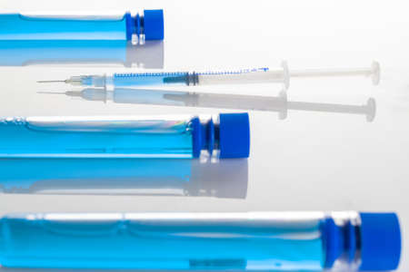 Vaccination bottle. Medical syringe with needle for protection flu virus and coronavirus. Covid vaccine on white. Concept: diseases, medical care, scienceの写真素材