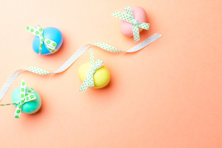 Easter holiday. Colorful egg with tape ribbon on pastel pink background in Happy Easter decoration....