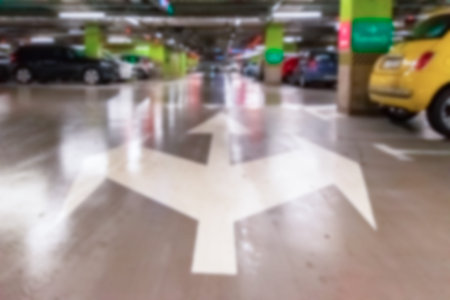Parking garage blurred. Empty road asphalt background in soft focus. Car lot parking space in...