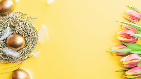 Easter eggs gold. Golden color egg in basket with spring tulips, white feathers on pastel yellow...