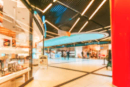 Bokeh Shopping mall background. Interior of retail center store in soft focus. People shopping in modern commercial mall center. Fashion market hallの写真素材